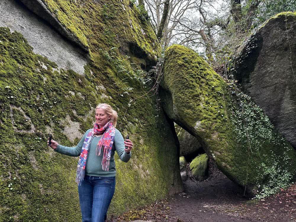 Eulalie Motte, baguettes coudées en main, dans un sous-bois aux rochers couverts de mousse
